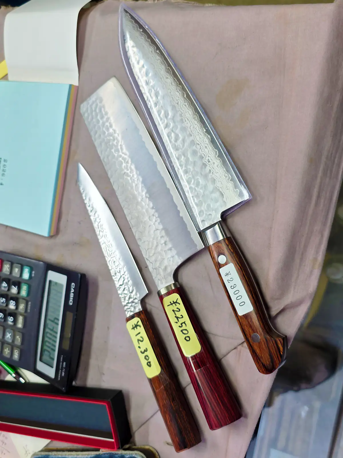 Drei japanische Küchenmesser mit unterschiedlichen Klingenformen auf dem Verkaufstresen bei Hayakawa Hamonoten