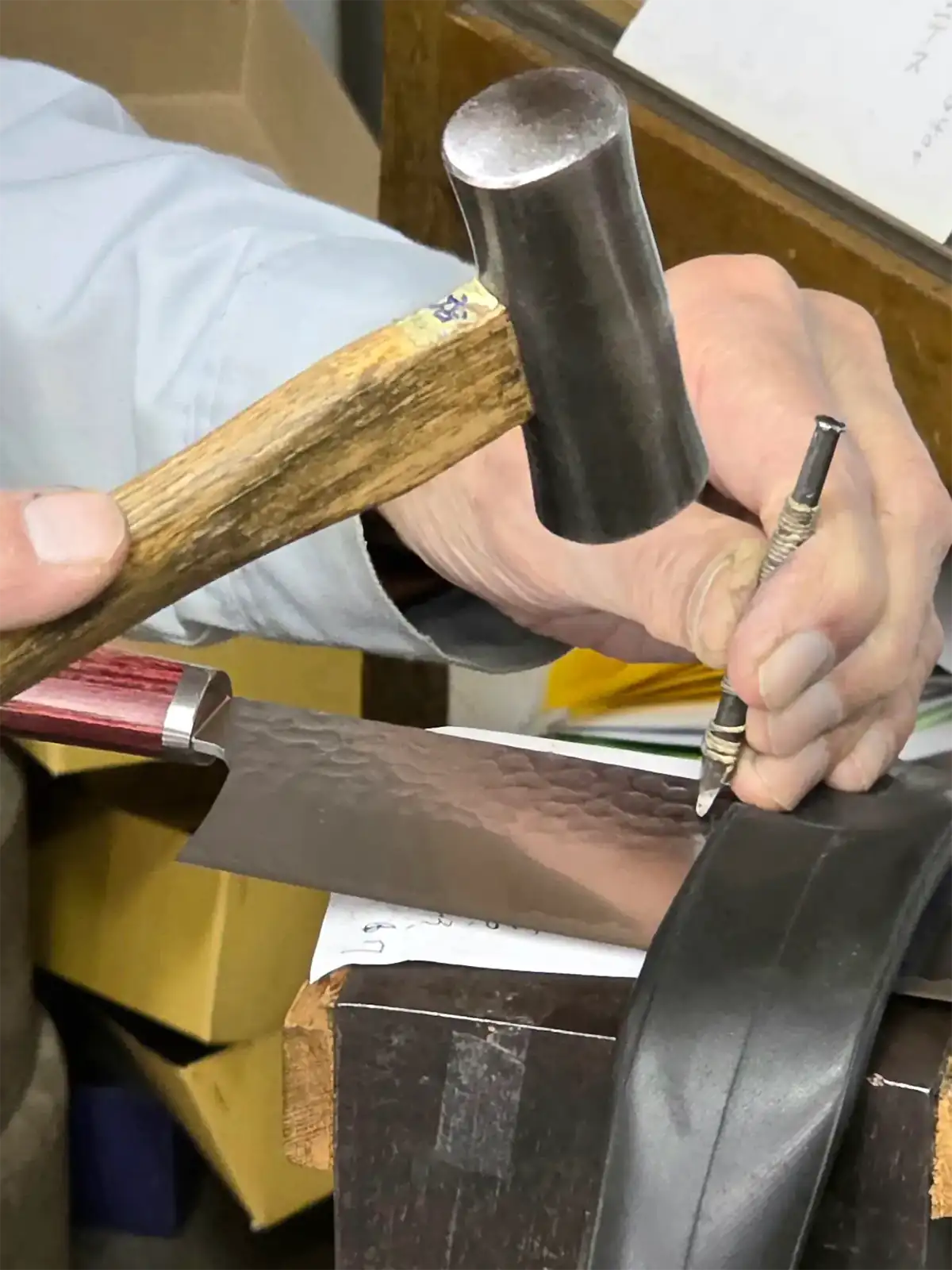 Nahaufnahme von Hammer und Punze bei der Handgravur eines japanischen Küchenmessers