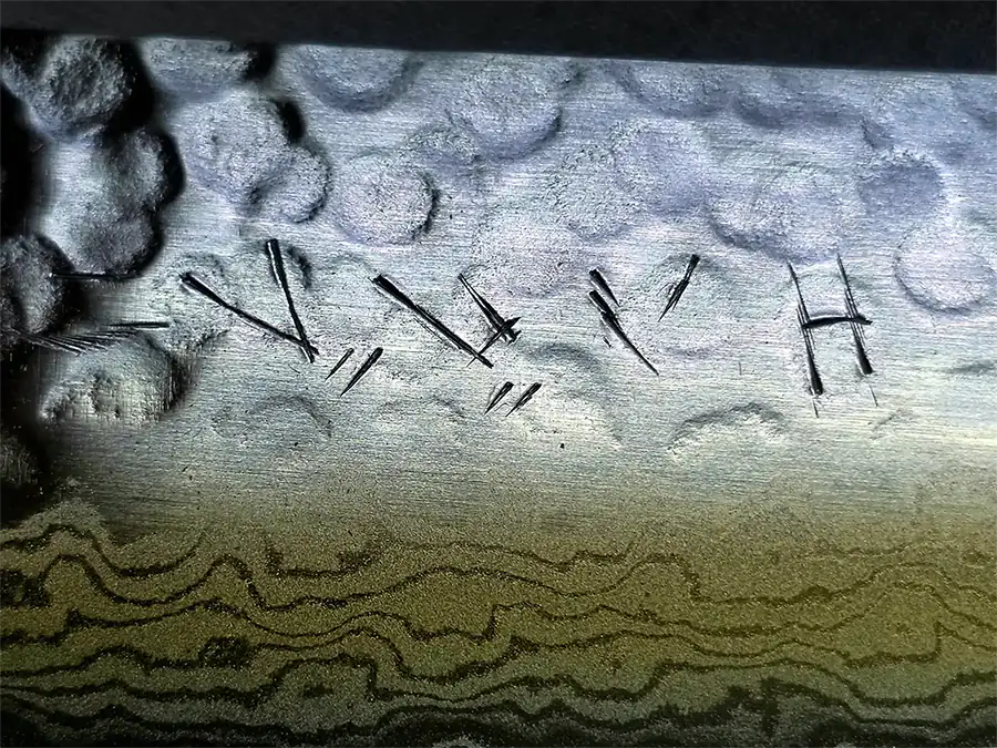 Nahaufnahme unseres in Katakana handgravierten Nachnamens auf einer Klinge aus gehämmertem Stahl