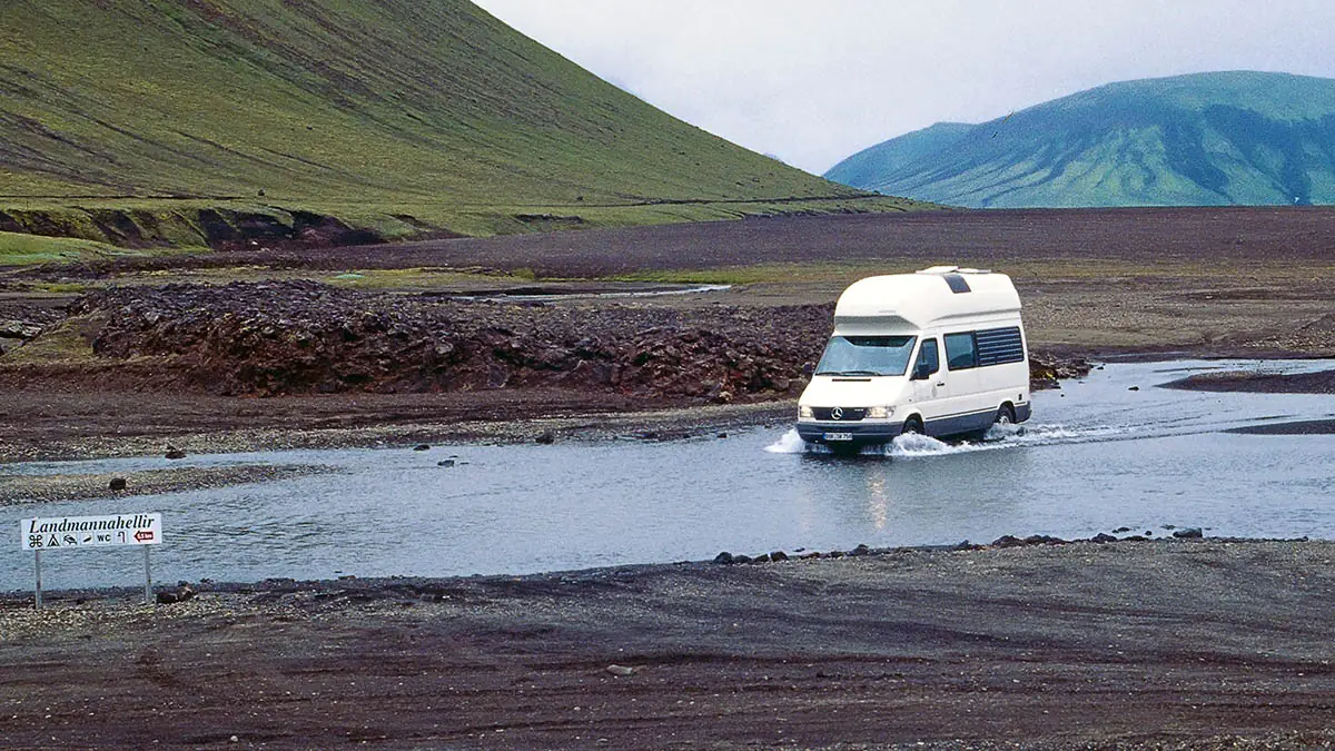 Weißer Westfalia James Cook bei einer Flussdurchquerung in Islands vulkanischer Landschaft